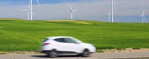 elektro automāšīna ar vēja ģeneratoriem fonā
